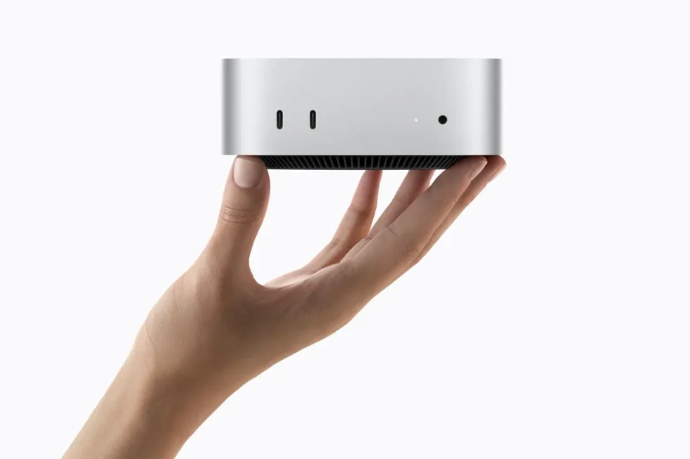 En hånd holder Mac mini op mod en hvid baggrund.